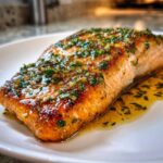 Close-up of a perfectly cooked Texas Roadhouse Garlic Butter Salmon fillet glistening with butter sauce and herbs.
