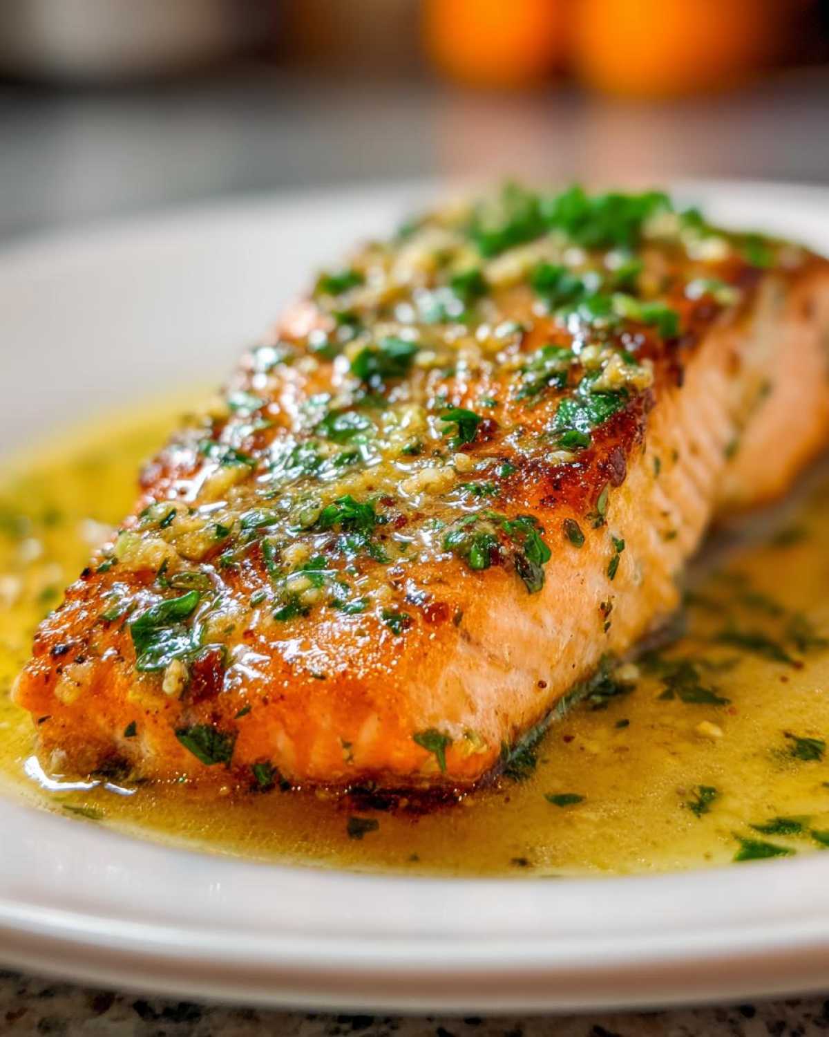 Close-up of a perfectly cooked Texas Roadhouse Garlic Butter Salmon fillet swimming in garlic butter sauce and topped with fresh parsley.