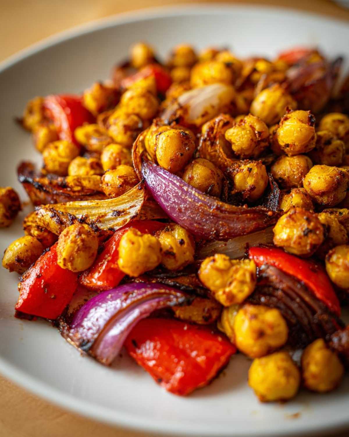 Close-up of roasted, spiced chickpeas mixed with charred red onion and red bell pepper from the Vegan One-Pan Chickpea Shawarma Sheet Bake.
