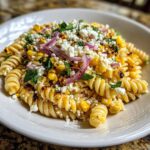 Close-up of Zesty Mexican Street Corn Pasta Salad with rotini pasta, charred corn, cotija cheese, and red onion.