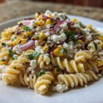 Close-up of Zesty Mexican Street Corn Pasta Salad featuring rotini pasta, charred corn, red onion, and crumbled cotija cheese.