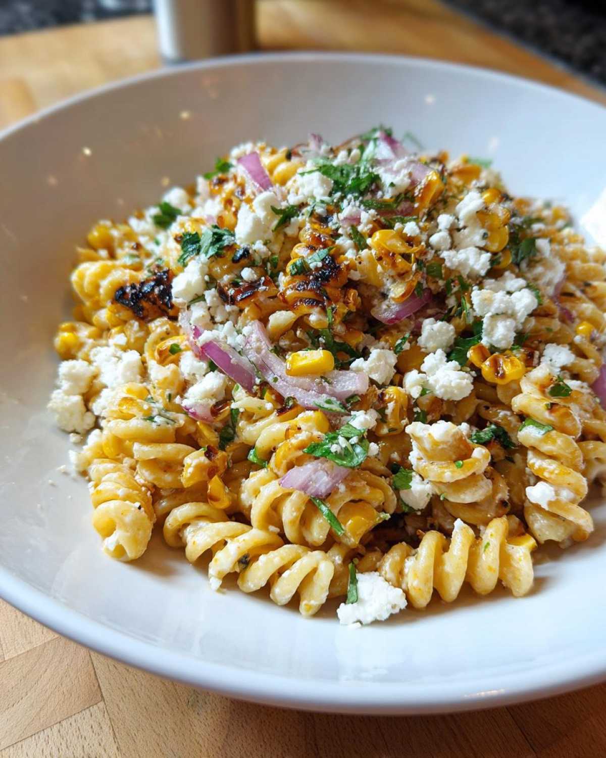 Close-up of Zesty Mexican Street Corn Pasta Salad featuring fusilli pasta, charred corn, cotija cheese, and red onion.